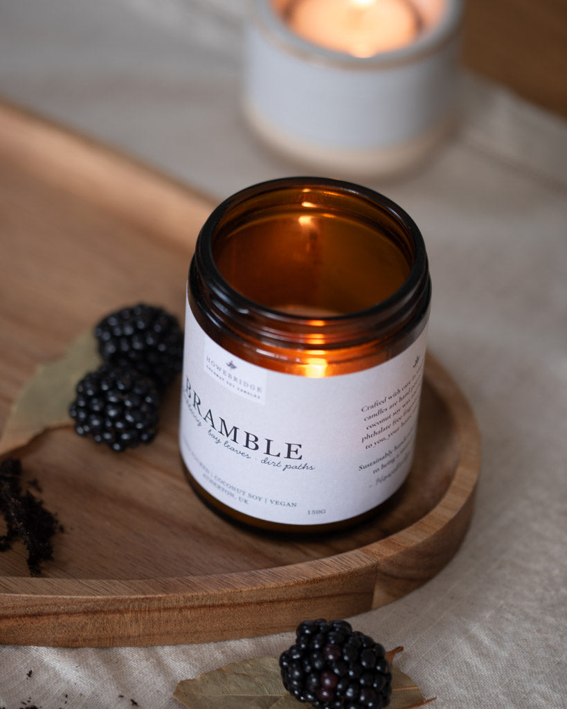 Blackberry candle lit surrounded by blackberried and bay leaves. Glass amber jar with natural off white label. Scent makes you feel like your blackberry picking in the forest, earthy, sweet but cosy.