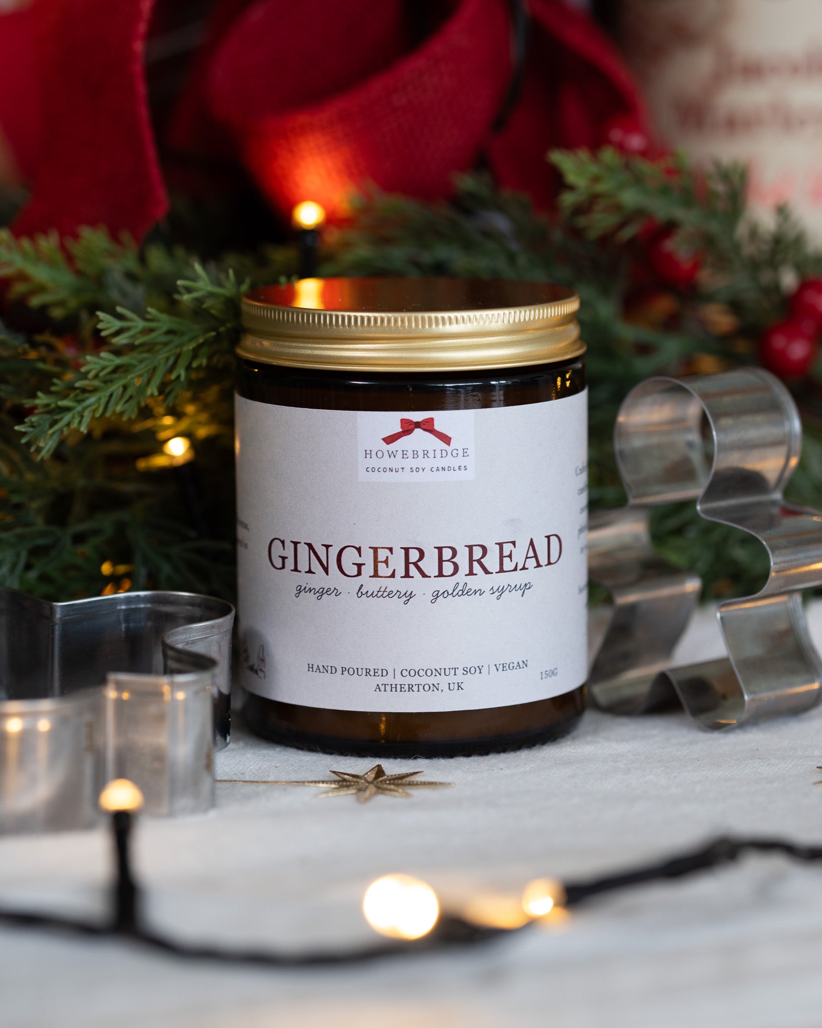 Gingerbread scented candle in a glass amber jar and gold lid. Wrapped in a festive label featuring a red bow with the scent of ginger, buttery cookies and golden syrup. Sustainably made, vegan friendly and gift ready.