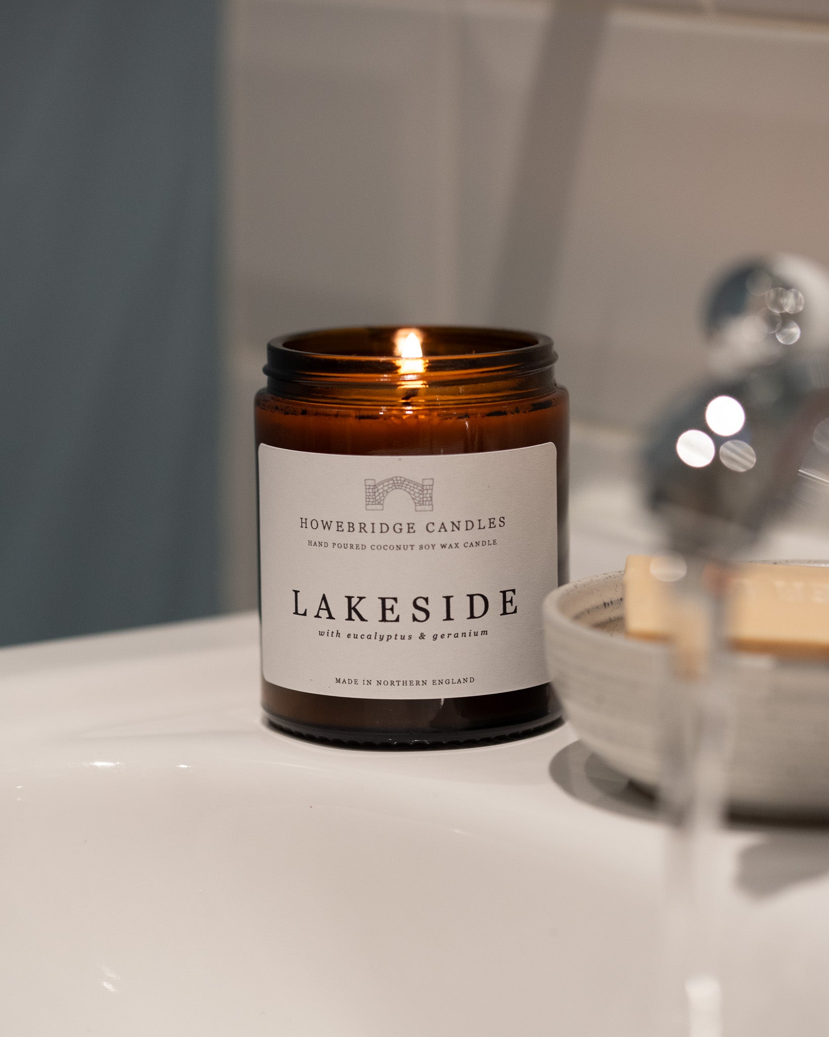 Glass amber candle labeled 'Lakeside' by Howesbridge Candles on a bathroom counter.