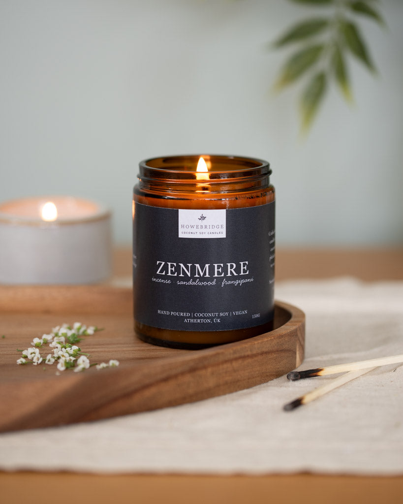 Zenmere candle in a glass jar with a wooden lid on a wooden tray. Scent incense, sandalwood and frangipani. Hand poured coconut soy wax. A rich Incense and slightly floral scent, the perfect candle to find inner balance, meditate or light during a yoga session.
