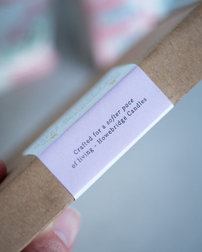 Close-up of a Howebridge Candles product with a label on a blurred background. Label says "crafted for a softer pace of living - Howebridge Candles".