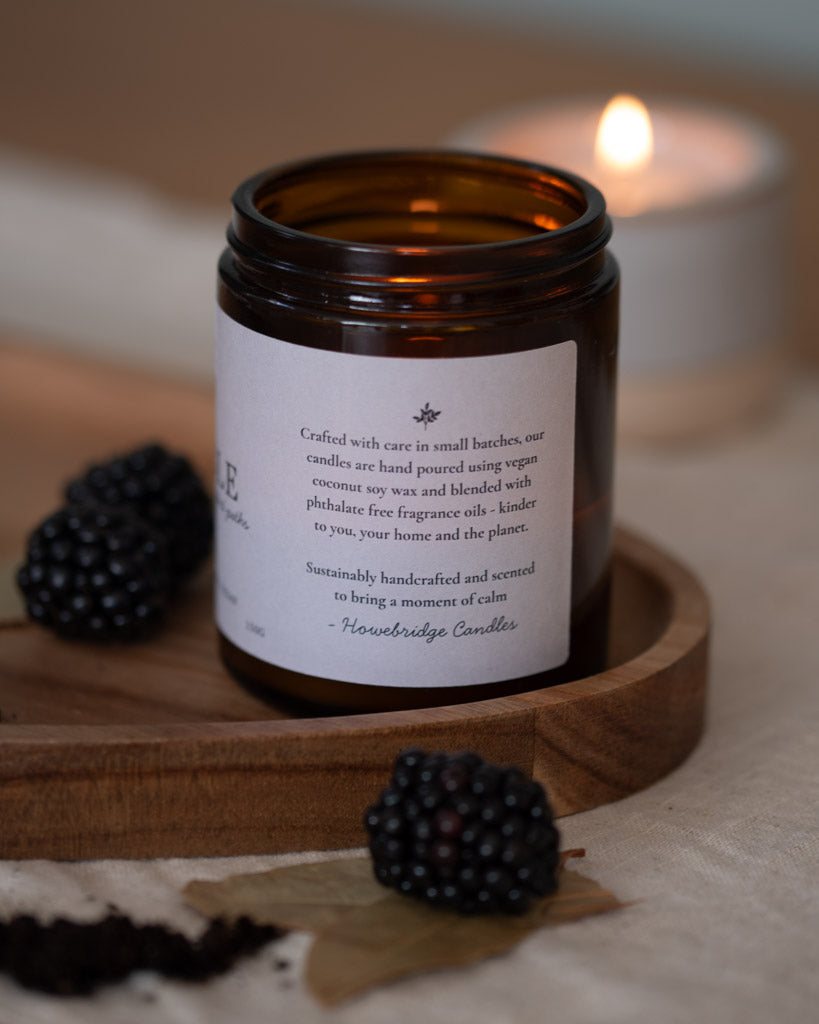 Amber glass candle jar with a off white natural label, close up image of the details on the side, with botanical logo. Talks about ingredients being coconut soy wax and phthalate free oils. How they're sustainable and kinder to you, your home and the planet.