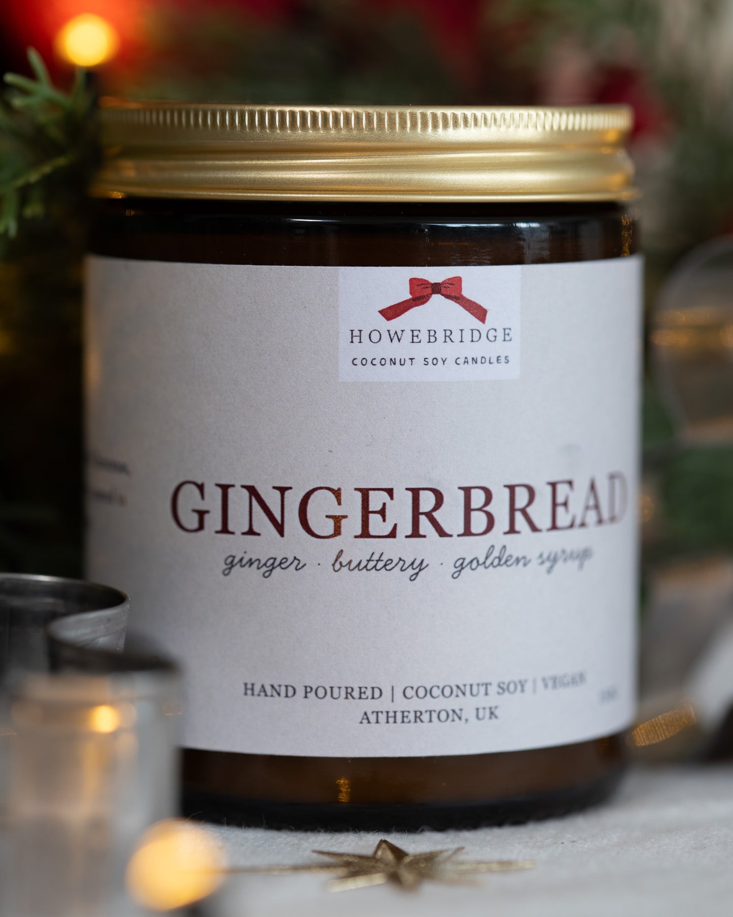 Gingerbread scented coconut soy wax candle. In a glass amber jar and gold lid. Wrapped in a festive label featuring a red bow and scent noted of ginger, buttery cookies and golden syrup. Vegan, sustainable and free from toxins.