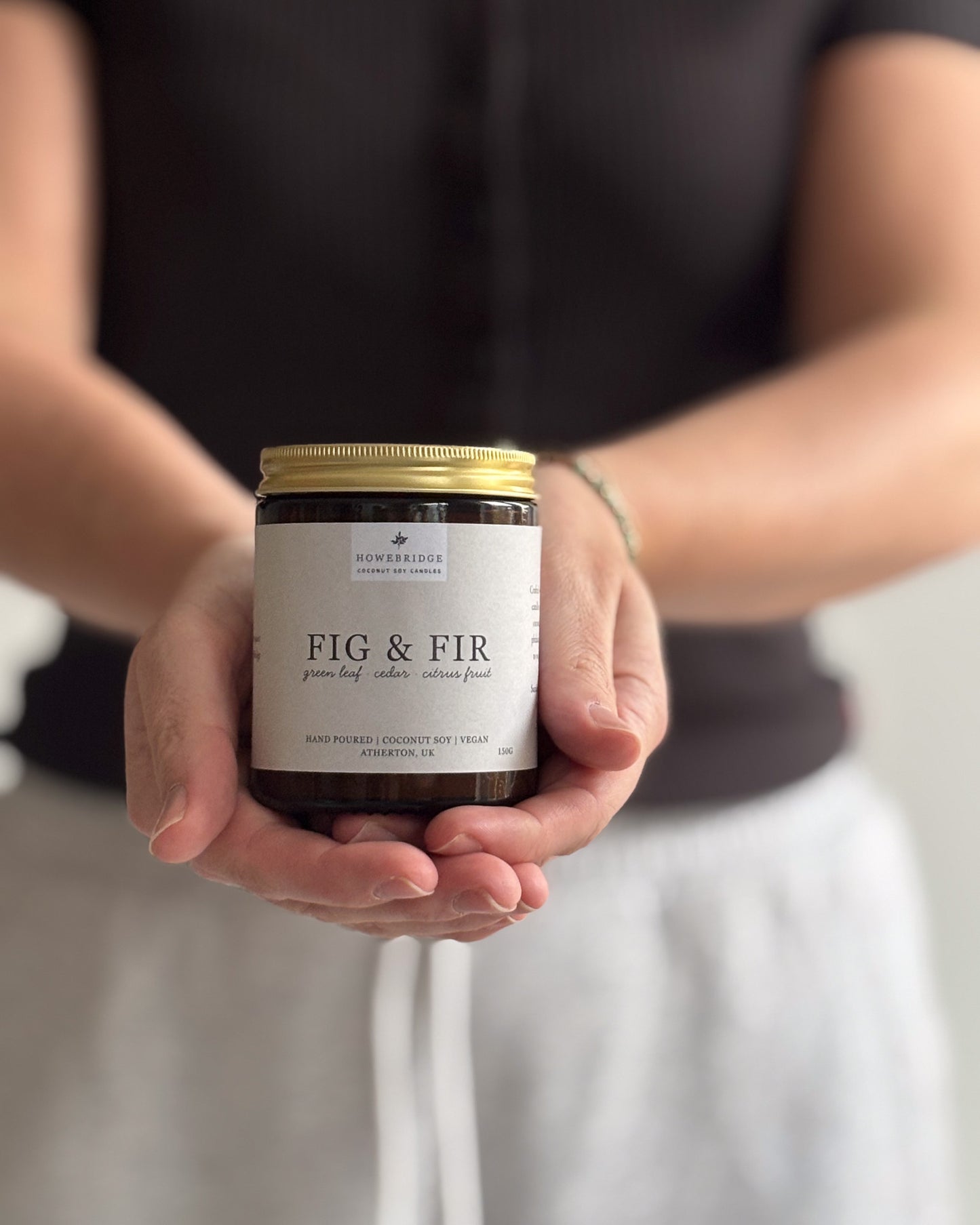 Howebridge candles, scent Fig & Fir. Hand poured in a glass amber jar and gold lid, wrapped in a beige label featuring botanical print.