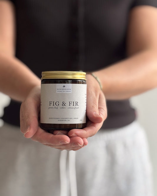 Howebridge candles, scent Fig & Fir. Hand poured in a glass amber jar and gold lid, wrapped in a beige label featuring botanical print.