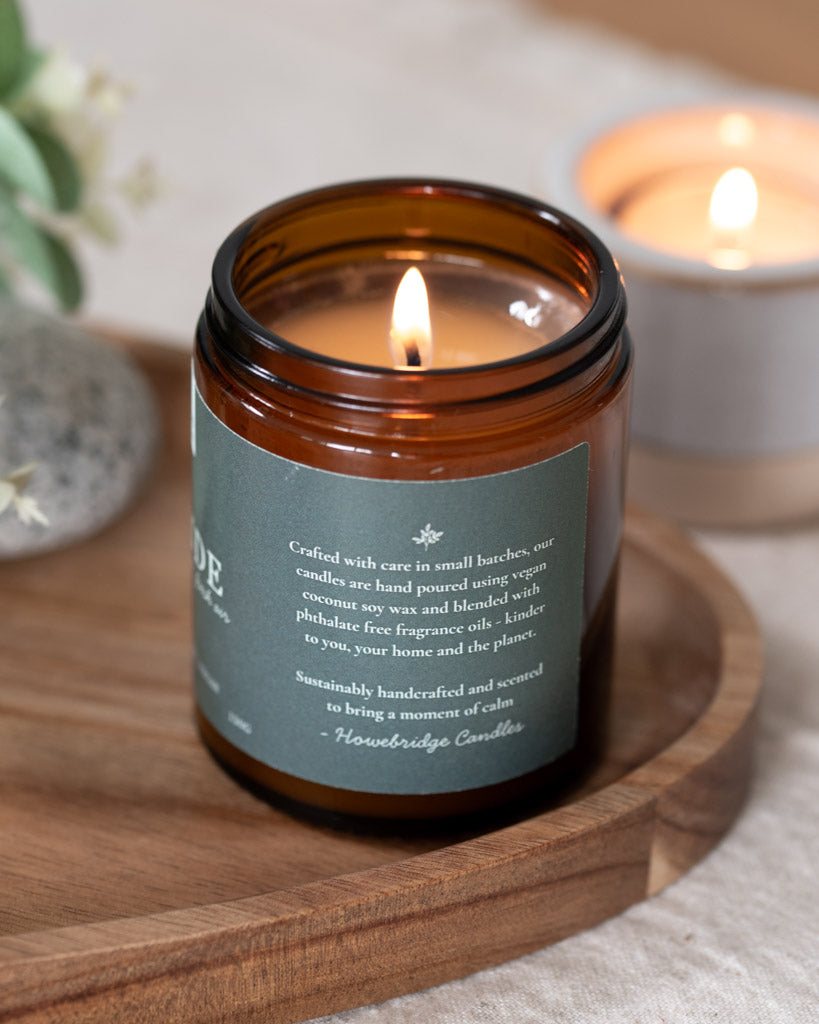 Lakeside amber jar candle with a sage green label. Image shows side of label and information about how the candle is made such as hand poured with coconut soy wax and phthalate free oils. Sustainable, vegan and eco-friendly. 