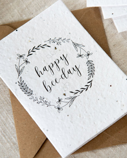 Wildflower plantable seed card with the message 'happy bee-day' and surrounded by botanicals and bees. Sustainable, eco-friendly and can be personalised.