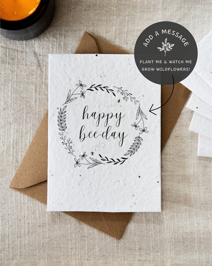 Wildflower plantable seed card with the message 'happy bee-day' surrounded by botanicals, leaves and bees. Printed on 100% cotton paper and complete with c6 kraft envelope. Can be personalised. Sustainable and eco-friendly.