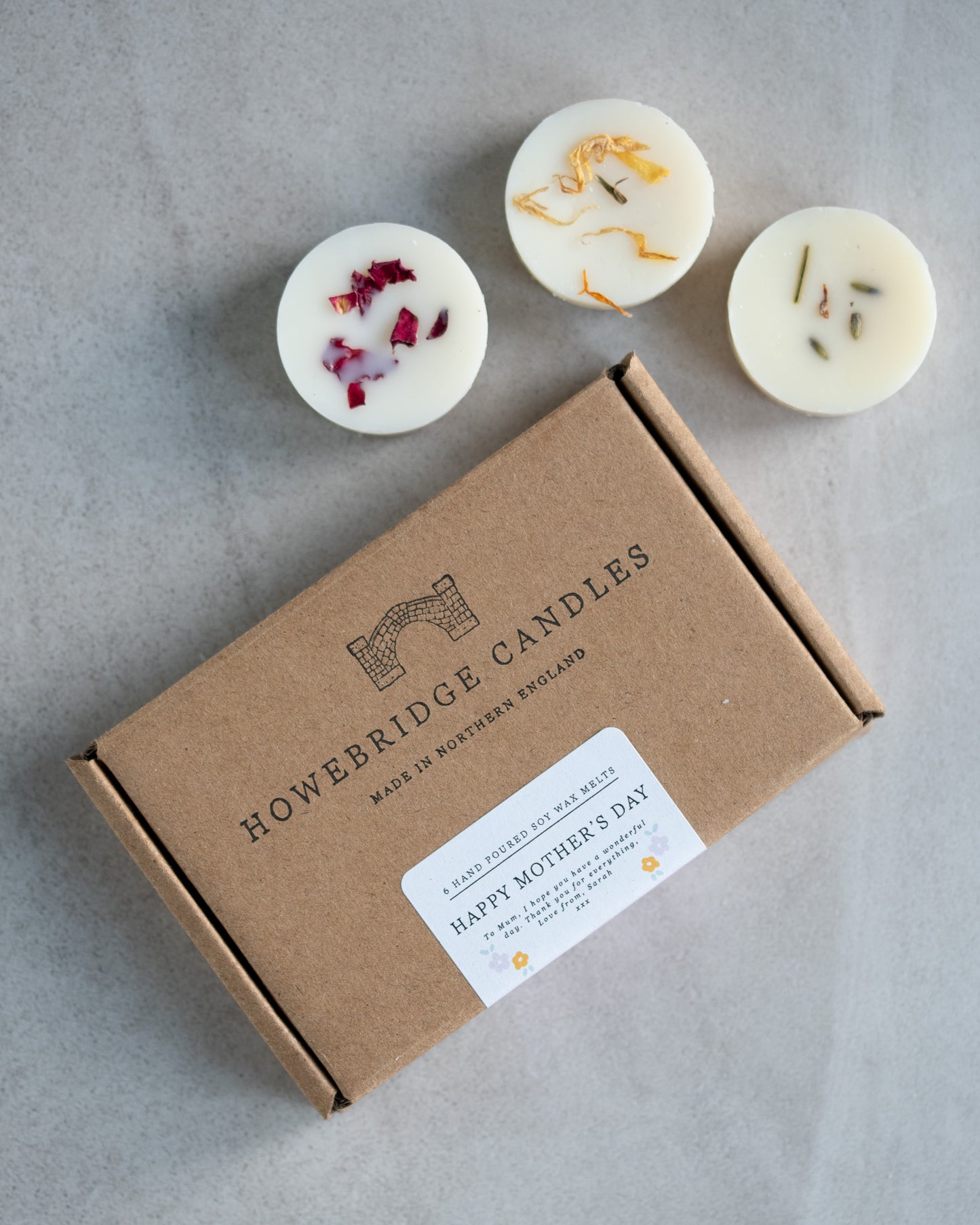 Howebridge Candles mother's day letterbox gift box, featuring stamped logo and sealed with a personalised label. Surrounded by soy wax melts and sprinkled with botanicals.