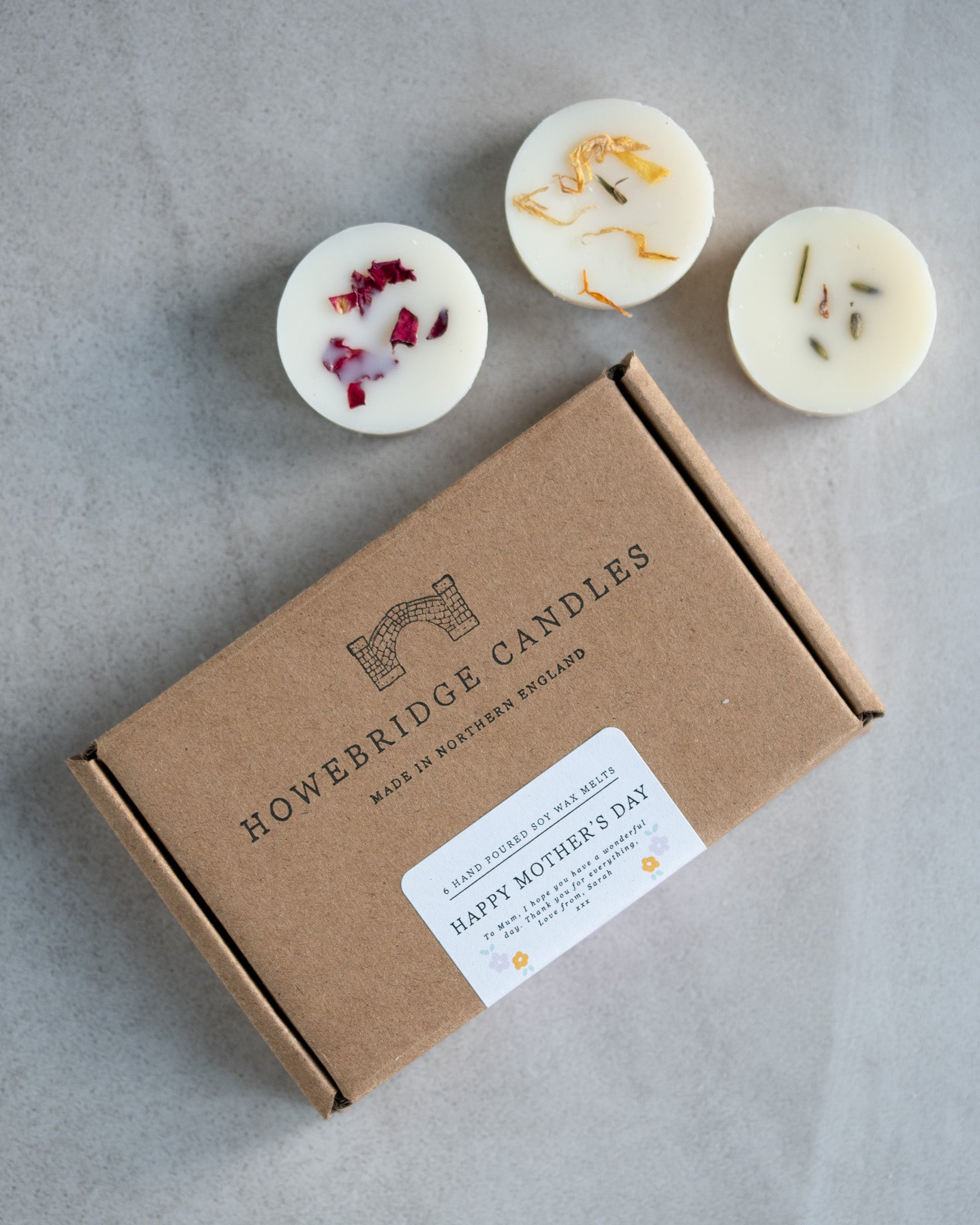 Howebridge Candles mother's day letterbox gift box, featuring stamped logo and sealed with a personalised label. Surrounded by soy wax melts and sprinkled with botanicals.