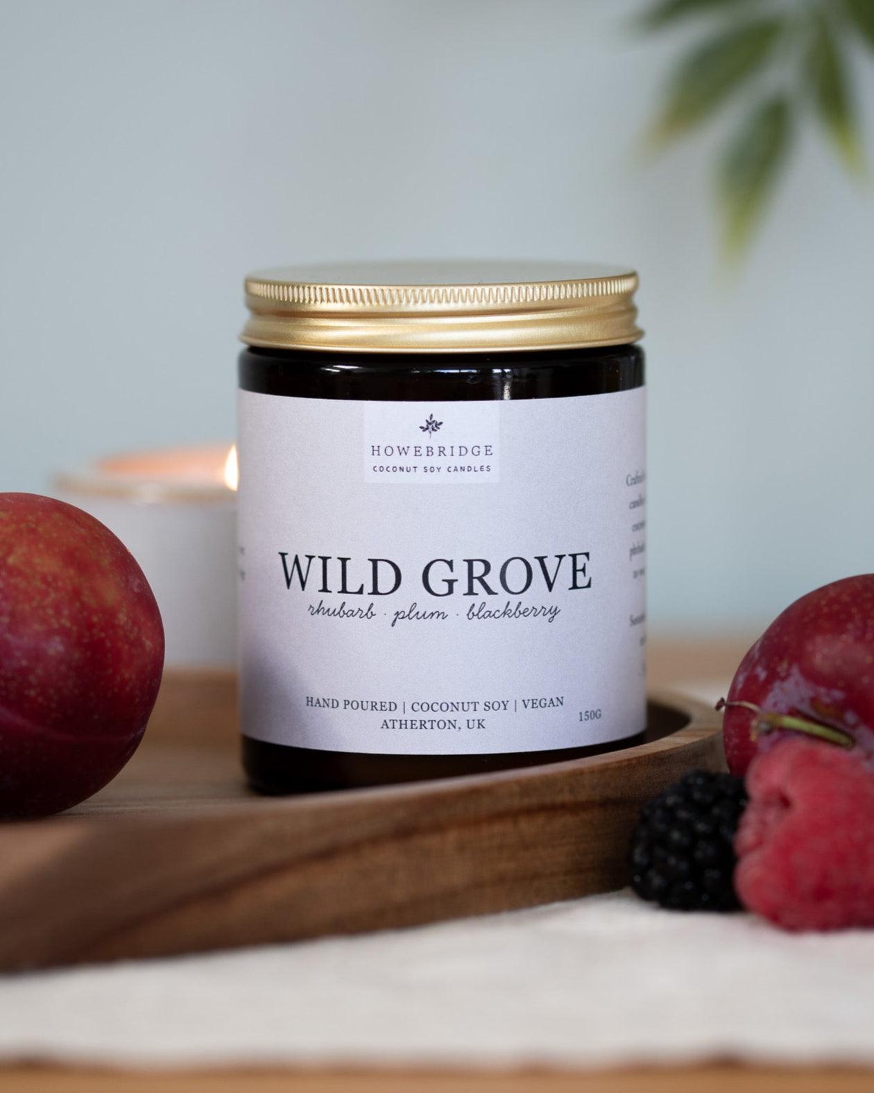 Wild grove candle surrounded by summer fruits. A glass amber jar with a natural off white label. Scent: Rhubarb, plum and blackberries. A sweet, fruity candles perfect for summer or a sweet pick me up.